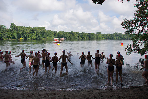 Schüler rennen vom Strand ins Wasser.