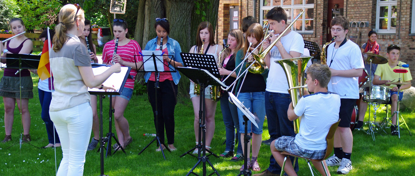 Schüler spielen Blasinstrumente auf der Wiese vor dem Fährhaus.